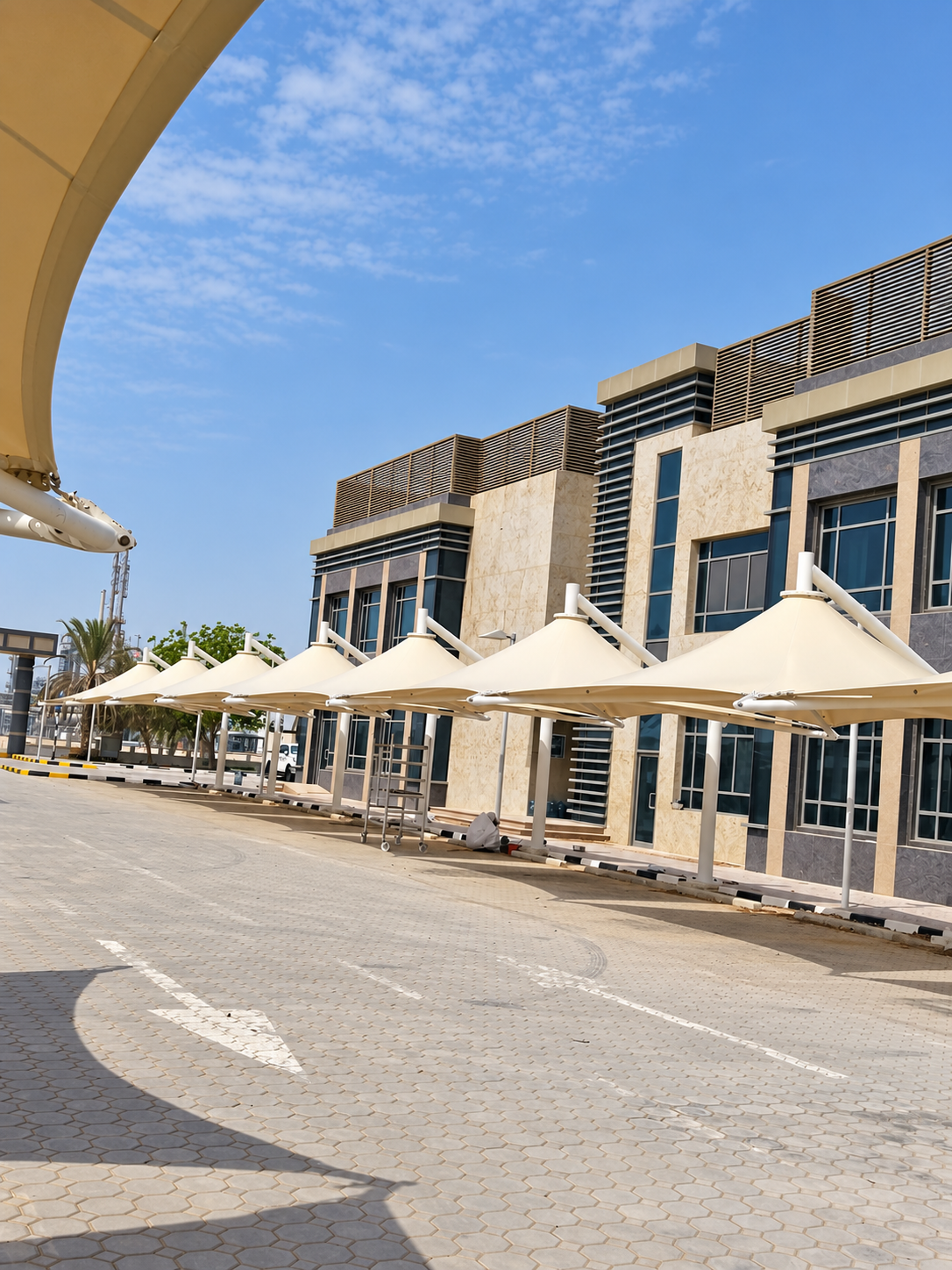 Beige tensile parking shades installed beside a building